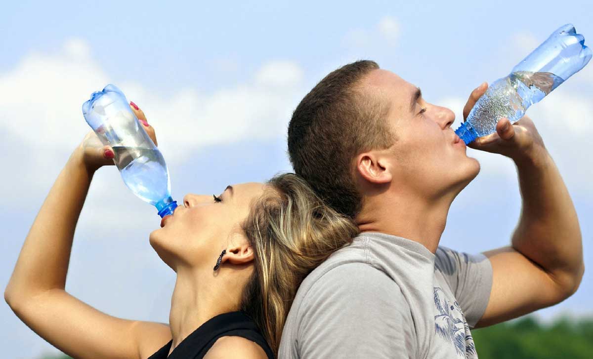man and woman drinking bottled water