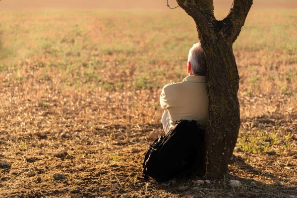 man sitting against tree