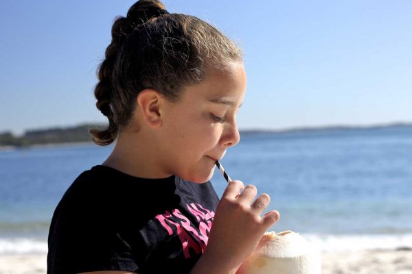 girl drinking coconut on the beach