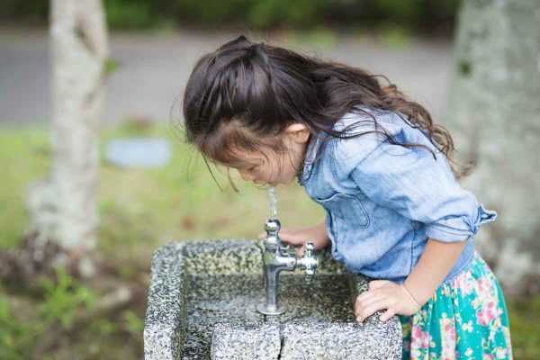 young girl drinking outside tap water