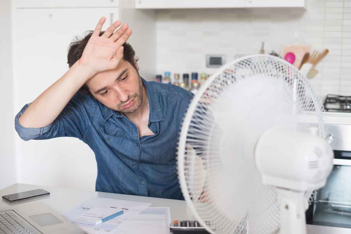 man using a fan to stay cool in the summer