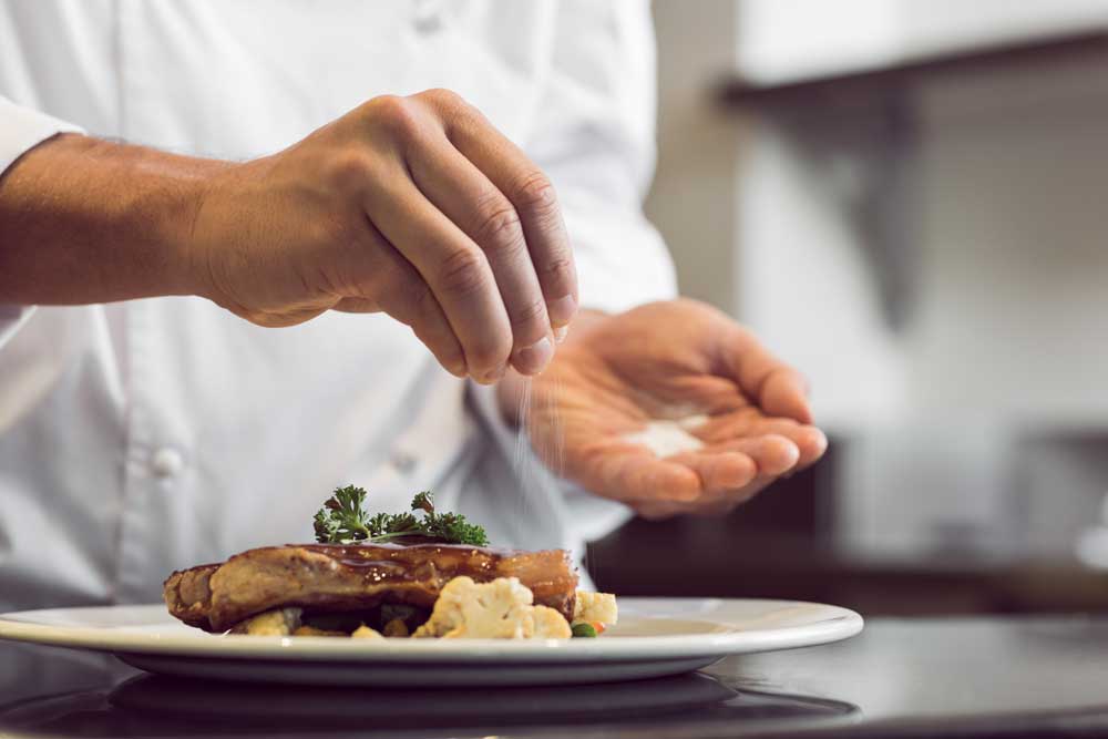 chef puts salt on steak for taste