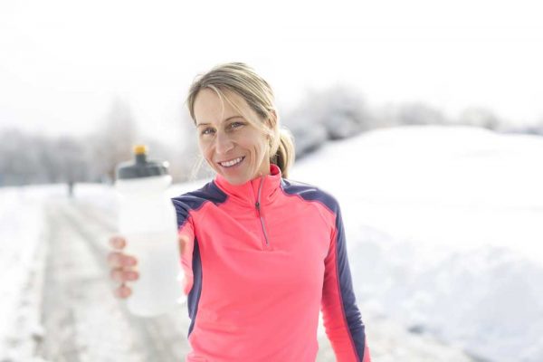 woman holding water bottle out in winter