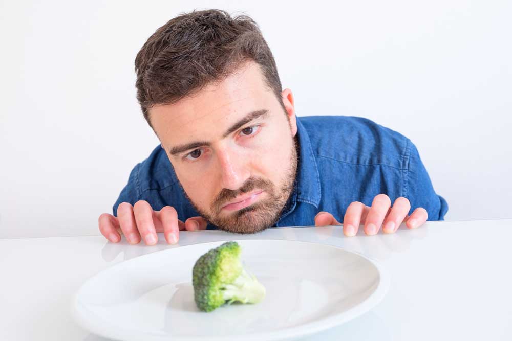 guy staring at vegetable on table