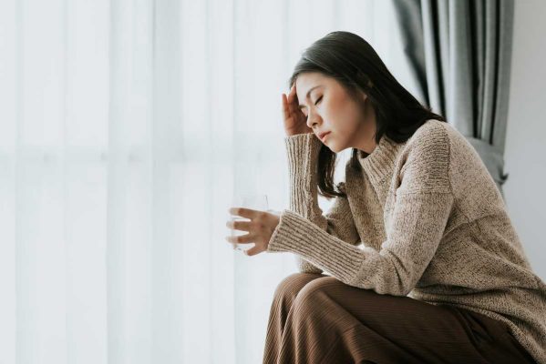 woman sitting on edge of bed with hangover